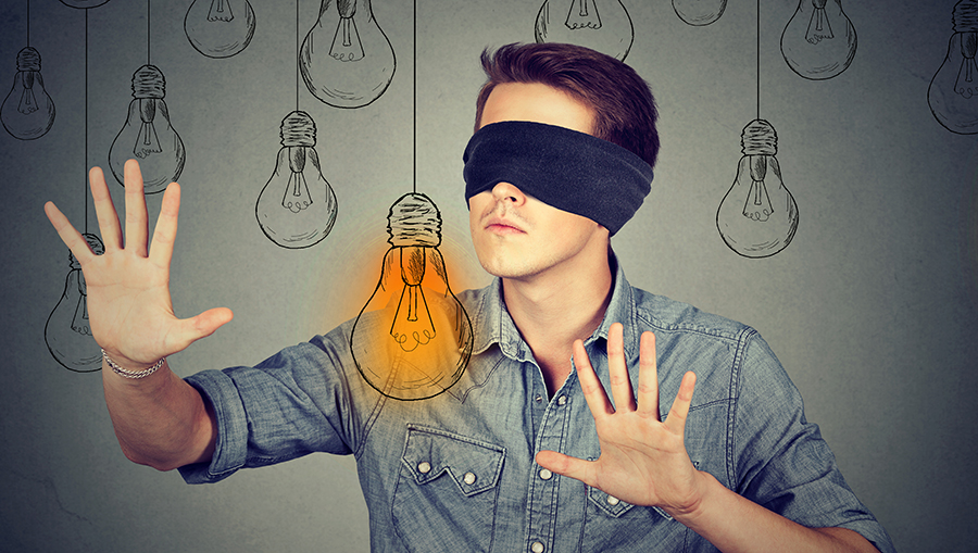 Young man, blindfolded, reaches for lightbulb